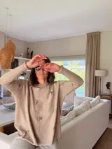 Sweater de viscosa color beige con diseño holgado, cuello redondo y mangas largas, decorado con pequeñas flores bordadas a mano en toda la prenda.