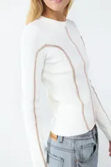 Sweater de manga larga color crudo, confeccionado en tejido de canalé elasticado. Diseño ajustado con cuello redondo y costuras decorativas en contraste color rosado en el frente, la espalda y las mangas.