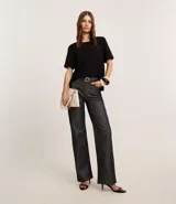 Blusa blanca de poliéster con cuello redondo, mangas cortas, cierre trasero en forma de gota, pequeñas aberturas laterales y acabados en pespuntes en las mangas y el cuello.