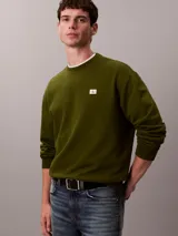 Buzo de cuello redondo Calvin Klein confeccionado en algodón regenerado de color verde militar, con interior de tejido terry, puños y cuello con punto canalé, y un pequeño parche con el monograma de la marca en el pecho.