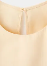 Vestido midi color beige, de cuello redondo y sin mangas, con diseño cruzado en la falda y lazo ajustable en la cintura.