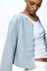 Chaqueta celeste de manga larga, con cuello redondo y frente abierto con bordes festoneados.