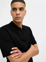 Polo de punto estructurado color negro, con cuello polo, cierre frontal parcial con cremallera y mangas cortas.