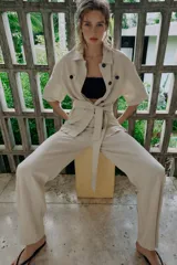 Pantalón de tiro medio confeccionado en lino color beige, de pernera recta con nervios marcados en el delantero. Posee bolsillos frontales, falsos bolsillos de vivo en la espalda y cierre frontal con cremallera, botón interior y gancho.