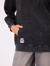 Canguro oversize color negro con efecto lavado, capucha y estampa gráfica en la espalda con tipografía desgastada y detalles en color turquesa.