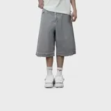 Bermuda baggy de denim gris, corte holgado y largo por debajo de las rodillas, con dobladillo desmechado.