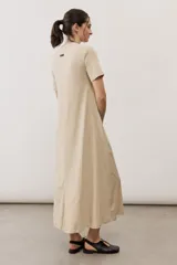 Vestido midi negro con diseño de manga corta, cuello redondo y bolsillos laterales, corte amplio y fluido.