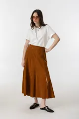 Falda midi de gamuza color marrón, con corte acampanado, tajo lateral y cierre metálico en el costado.