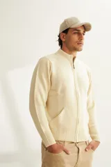 Campera tejida color marrón claro con cierre delantero, cuello alto y bolsillos delanteros. Tejida en 100% lana fina sin teñir.