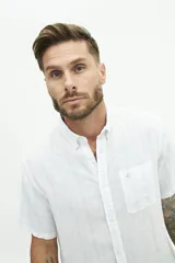 Camisa de manga corta confeccionada en lino y algodón, con fit regular y logo bordado. Color beige con rayas verticales blancas.