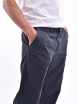 Pantalón de vestir azul oscuro, de corte recto, con bolsillos laterales y traseros. Se ajusta a la cintura con cinturón de cuero marrón.
