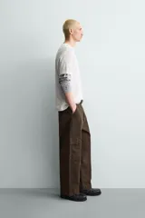 Pantalón cargo de corte relajado confeccionado en tejido de algodón con elasticidad. Presenta bolsillos laterales tipo cargo con solapa en las perneras, bolsillos frontales y bolsillos traseros de doble vivo. Cierre frontal con cremallera y botón.