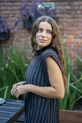 Chaleco tejido de punto acanalado vertical en color negro con hilos de lurex plateados. Presenta cuello redondo, hombros amplios con efecto de hombrera caída y tajos laterales en el ruedo.