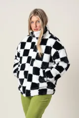 Campera de poliéster símil piel, con estampado a cuadros blancos y negros, cierre frontal y bolsillos laterales.