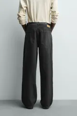 Jeans baggy fit de corte holgado en color negro con efecto lavado, confeccionados en denim de algodón rígido, con diseño clásico de cinco bolsillos y cierre frontal con cremallera y botón.
