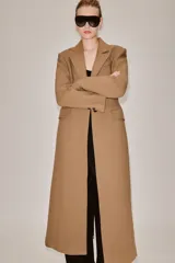 Abrigo largo entallado de Zara Woman Collection, confeccionado en mezcla de lana color tostado. Presenta cuello con solapa de muesca, mangas largas, bolsillos con solapa en el frente, forro interior y cierre frontal de dos botones oscuros.