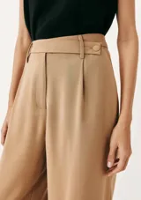 Pantalón de vestir de corte recto y tiro alto, con cierre frontal y trabillas para cinturón. Presenta pinzas en la parte delantera que aportan estructura a la prenda.