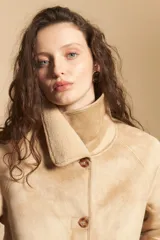 Gamulán de gamuza sintética color marrón con interior de corderito al tono. Presenta cuello amplio, cierre frontal con botones y diseño de silueta relajada.