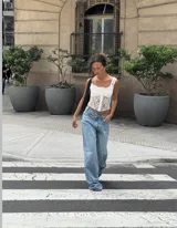 Corset de encaje negro con diseño floral, copas estructuradas y cierre frontal con botones a presión. Presenta breteles anchos de encaje y espalda con diseño de red.