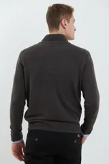 Sweater verde oliva de tejido acrílico con textura similar al cashmere, corte clásico, cuello alto con cierre metálico y tirador de cuerina ecológica.