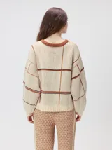 Sweater de punto con diseño geométrico y gráfico frontal en color rojo. Presenta cuello redondo, mangas largas holgadas y un ajuste suelto.