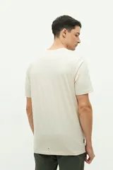 Remera de manga corta color beige con estampado gráfico frontal de la marca Brooksfield en tonos grisáceos, con diseño de estilo vintage y tipografía clásica.