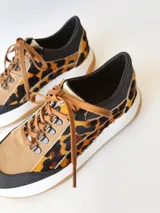 Championes deportivos de cuero con estampado animal print, cordones marrones y suela blanca con base color caramelo.