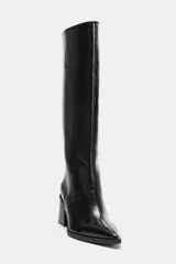 Bota alta de caña media con acabado brillante, tacón cuadrado y punta fina. Diseño minimalista con costura vertical lateral y estilo pull-on.