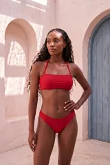 Conjunto de bikini rojo con corpiño bandeau con tirantes finos ajustables al cuello y bombacha clásica de tiro medio.