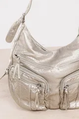 Bolso hobo negro de cuero sintético con textura arrugada. Tiene correa de hombro, cierre superior y múltiples bolsillos frontales con cierre.