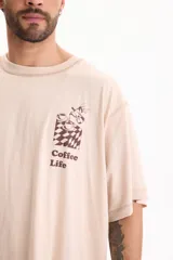 Remera de algodón de manga corta, fit oversize, color beige con estampa en el pecho con diseño de café y texto "Coffee Life".