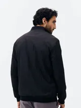 Campera bomber negra con cierre frontal, cuello, puños y dobladillo en rib elástico, y bolsillos laterales.