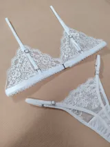 Conjunto de lencería de encaje blanco, compuesto por un soutiene triangular sin relleno con tirantes regulables y una bombacha colaless ajustable con detalles de encaje.
