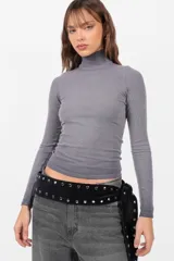 Top de morley gris de manga larga, con cuello media polera y largo de camiseta. Presenta un teñido en las terminaciones que crea un efecto degradado.