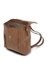 Mochila de cuero sintético color caramelo con solapa frontal, cierre principal y bolsillos laterales con tiradores largos. Incluye asa superior y logo de la marca grabado en la parte inferior.
