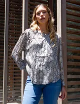 Blusa de gasa estampada con diseño animal print en tonos grises y blancos. Tiene cuello redondo, abertura central con botones dorados y musculosa interna.