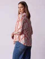 Blusa estampada blanca con diseño de cadenas y círculos color naranja. Cuello redondo con escote en V y lazo de ajuste. Manga 3/4.