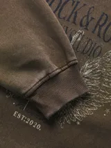 Buzo de cuello redondo color negro con lavado desgastado, de manga larga y fit relajado. Presenta una gran estampa frontal con la leyenda 'WILD & FREE' y gráficos de estilo vintage inspirados en el motociclismo.