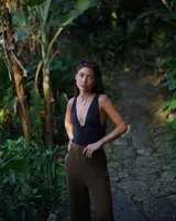 Collar con dije colgante de forma orgánica e irregular, acabado dorado, suspendido de un cordón negro de algodón natural.