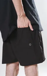 Short de baño negro de calce regular, confeccionado en textil plano liviano de secado rápido. Cuenta con cintura elástica con cordón ajustable, cuatro bolsillos y detalles de ojalillos metálicos laterales.