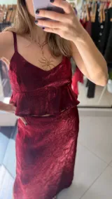 Falda midi de corte recto, confeccionada en tela satinada con textura arrugada en color bordó. Presenta un diseño elegante y fluido.