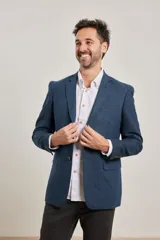 Blazer azul de corte slim, confeccionado en tejido con mezcla de lana. Tiene cuello con solapas, manga larga con puños abotonados, bolsillos de solapa en la cadera, abertura en la espalda y cierre frontal con botones.