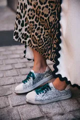 Zapatillas urbanas plateadas con glitter, puntera y talón en cuero blanco, cordones de raso verde esmeralda y suela blanca.