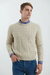 Sweater de tejido de punto color beige claro, con diseño de trenzas (aranes) en el frente y mangas de punto liso. Tiene cuello redondo.