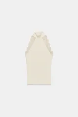 Top ajustado de tejido acanalado color crema, con cuello perkins y sisa adornada con aplicación de encaje a tono.