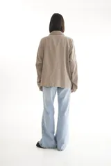 Camisa negra de pana, corte oversize, con cuello camisero, cierre frontal con botones, dos bolsillos con solapa en el pecho y mangas largas con puños abotonados.