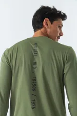 Remera verde militar de manga larga, cuello redondo y corte recto. Estampa pequeña en el pecho con texto en negro.