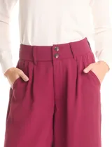 Pantalón tipo palazzo de corte ancho y fluido, confeccionado en tejido sastrero. Presenta tiro alto con doble abotonadura frontal, pinzas decorativas y cintura elástica en la parte posterior. Incluye bolsillos laterales funcionales.