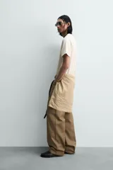 Camiseta relaxed fit color gris oscuro, confeccionada en tejido ligero de algodón con elasticidad. Presenta cuello redondo y manga ranglán corta.