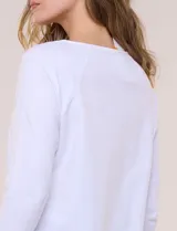 Remera blanca de algodón con elastano, de corte semi holgado, escote bote con ojalillos metálicos frontales, mangas tres cuartos raglán y ruedo asimétrico curvado.